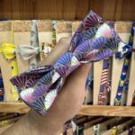 Banda para cabello de seda con diseño de fans en tonos morados, dorados, rosas y blancos, ideal para accesorios de moda.