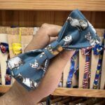 Lazo para mascotas con estampado de gatos de colores en tela azul.