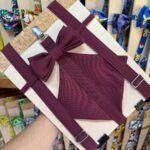 Lazo para cabello burdeos con fondo de madera y accesorios de bolsas de personajes de videojuegos.