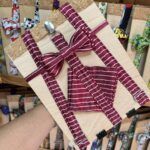 1. Correa para perros a rayas en color burdeos y blanco, con lazo decorativo y hebillas metálicas.