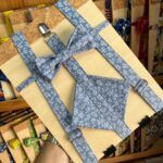 Decoración infantil con tirantes y pajarita de tela azul con estampado floral, ideal para eventos y ceremonia.