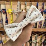 1. Listón de tela con lazo de puntos en tonos beige y morado, ideal para accesorios de moda y manualidades.
