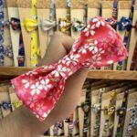 Colorido lazo para cabello con estampado floral y detalles dorados.