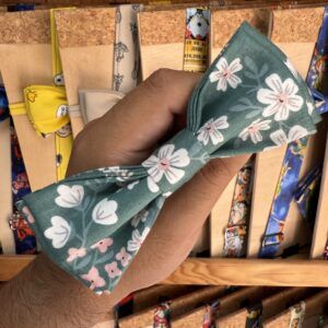 Asa de tela con flores blancas y fondo verde, ideal para accesorios de moda y complementos artesanales.