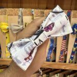Colorido lazo de tela con impresión de mariposas y letras, ideal para accesorios y decoraciones.