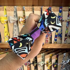 Colorido lazo de tela con diseño de personajes y patrones llamativos, ideal para accesorios de moda y bisutería.