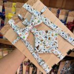 Arnés y lazo de tela con estampado de instrumentos musicales, en tienda de artesanías y accesorios creativos.