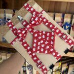 Lámina de regalo con cinta y lazo en tela con estampado de elefantes blancos sobre fondo rojo.