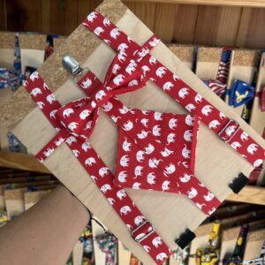 Lámina de regalo con cinta y lazo en tela con estampado de elefantes blancos sobre fondo rojo.