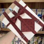 Correa de petaca en tela roja con estampado de pequeños motivos negros.