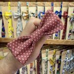 Colorido lazo de tela con estampado de flores blancas sobre fondo rojo, ideal para accesorios y manualidades.