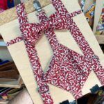 1. Correas de peto con estampado floral rojo y blanco para niña, en madera y accesorios metálicos.