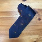 Corbata azul con diseño de dinosaurios verdes y rojos, elegante y original para ocasiones especiales.