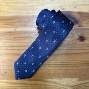 Corbata de seda azul con estampado de pequeños zigzags blancos y detalles dorados elegantes.