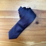 Cárcel de corbata azul marino en madera rústica para eventos formales.
