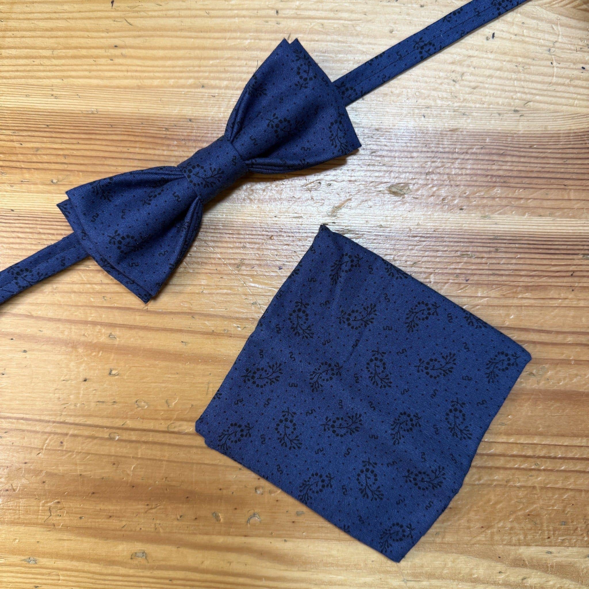 Tamaño de la pajarita y pañuelo de traje azul con estampado floral para eventos formales.