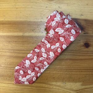 Funda de tela con diseño de hojas en tonos rojos y blancos, perfecta para protección y estilo.