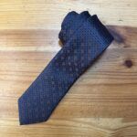 Corbata de seda con diseño geométrico en tonos azul marino y detalles en beige.