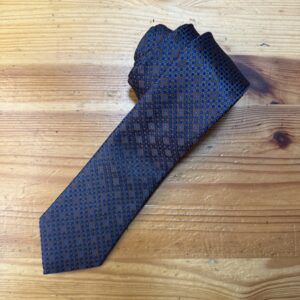 Corbata de seda con diseño geométrico en tonos azul marino y detalles en beige.
