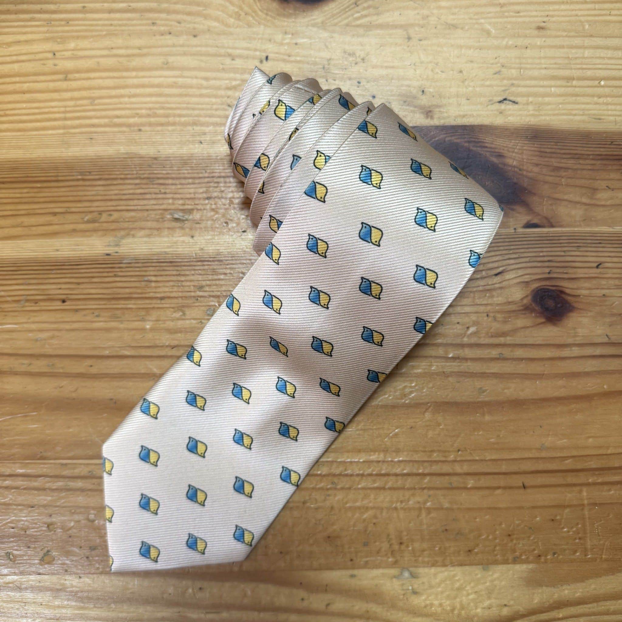 1. Corbata de seda color beige con patrón de pequeños diamantes azules y amarillos.