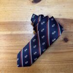 Cámara con corbata azul con anclas blancas y rayas rojas y blancas, estilo náutico elegante.
