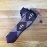 Corbata de diseño con calaveras y patrones geométricos en tonos morados y verdes, perfecta para estilos atrevidos y originales.