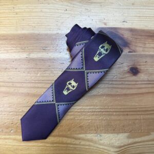 Corbata de diseño con calaveras y patrones geométricos en tonos morados y verdes, perfecta para estilos atrevidos y originales.