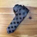 Cinturón de seda gris con diseño geométrico negro para ocasiones formales y elegantes.
