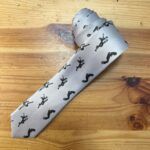 Corbata de satén con estampado de figuras femeninas en acción, diseño elegante y moderno, ideal para eventos formales y casuales.