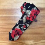 Tira de tela con estampado floral rojo y verde sobre fondo negro para accesorios de moda.