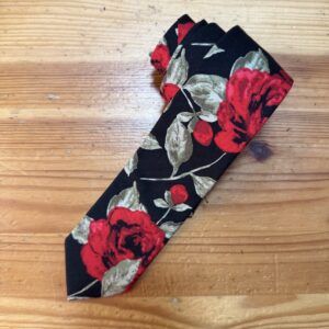 Tira de tela con estampado floral rojo y verde sobre fondo negro para accesorios de moda.