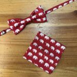 1. Corbatín y paño de tela con estampado de elefantes blancos en fondo rojo.