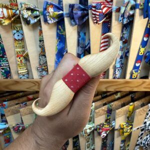 TÍTULO: Mordedor de madera con cinta roja y estampado de puntos, ideal para bebés y niños pequeños.