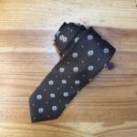 Corbata negra con estampado de margaritas y puntos dorados para hombre y mujer.