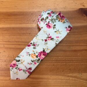 Colorido lazo de tela con estampado floral en rosa, amarillo y verde sobre fondo blanco, ideal para accesorios de moda y decoración.