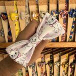 1. Lazo para mascotas con diseño de gatito adorable y accesorios variados en fondo de madera.