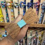 Colgante de madera en forma de lazo con grabado geométrico, ideal para accesorios únicos y artesanales.