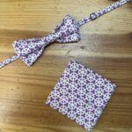 Corbata, pajarita y pañuelo a juego en tela morada con diseño geométrico blanco.