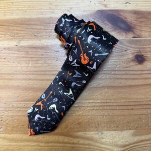 Goma de mascar con diseño musical y guitarra en colores naranja, negro y gris.