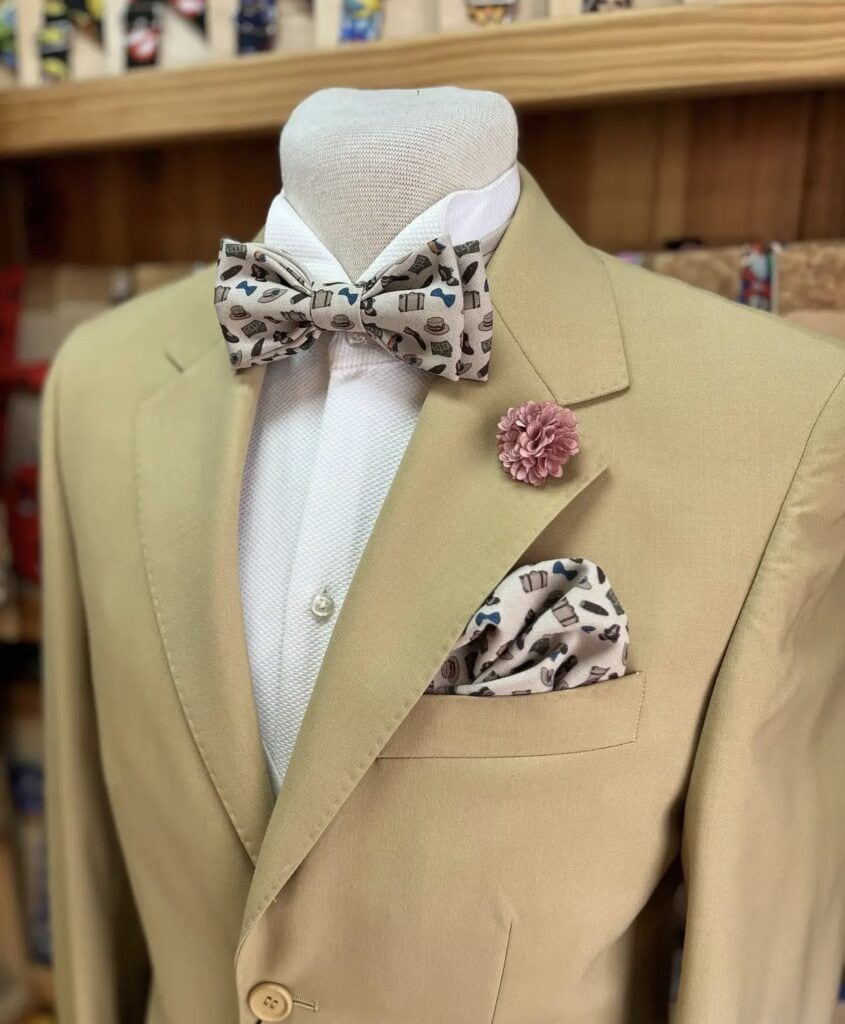 1. Traje de boda beige con pajarita y flor en el saco, para eventos formales y elegantes.