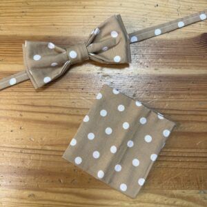 Corbata de moño beige con lunares blancos y pañuelo a juego, accesorios elegantes y modernos.