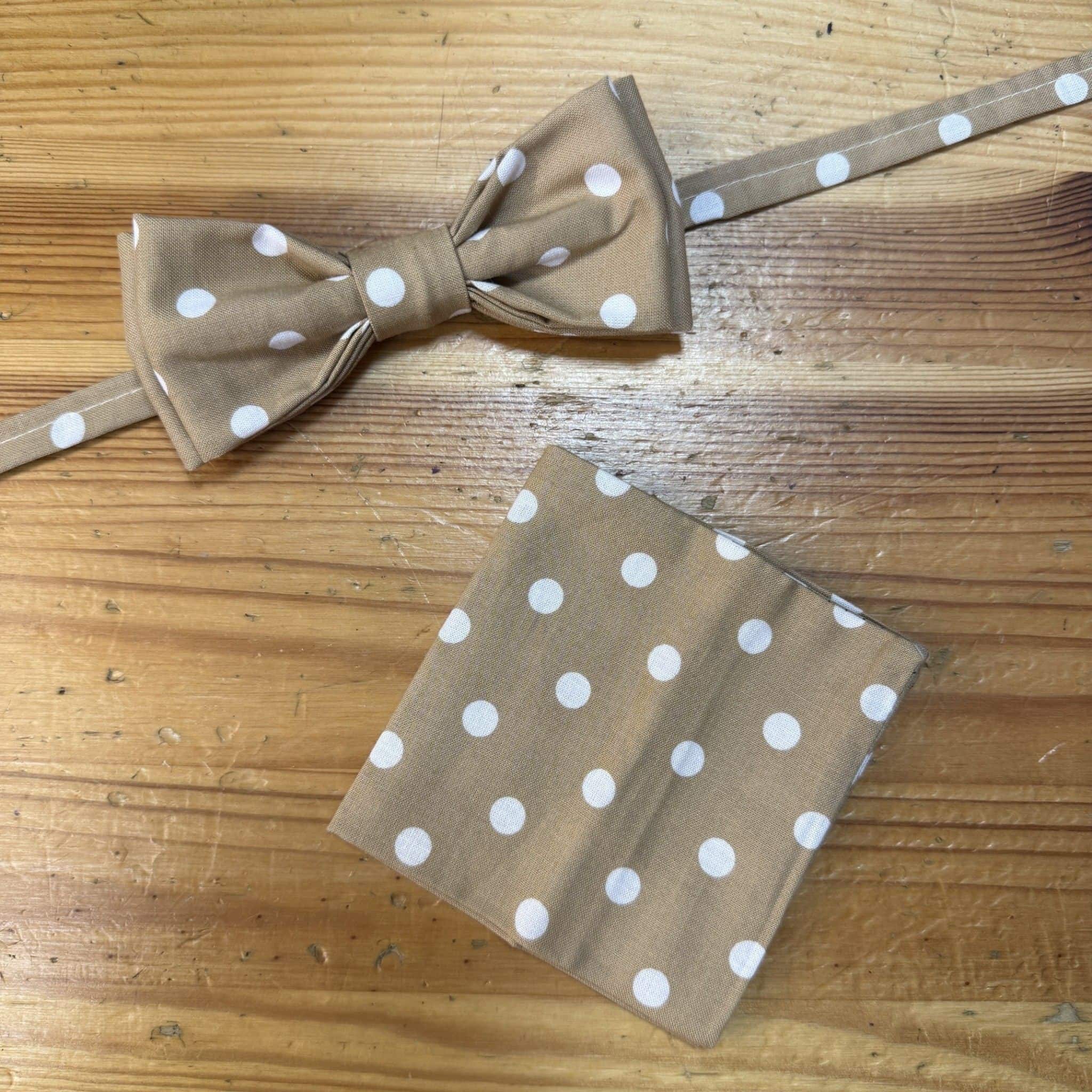 Corbata de moño beige con lunares blancos y pañuelo a juego, accesorios elegantes y modernos.