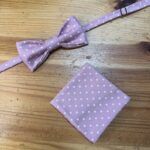 Lazo de moño rosa con puntos blancos y pañuelo a juego en madera natural, ideal para accesorios de moda y complementos juveniles.