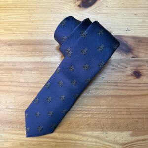 Elegante corbata azul con monogramas negros, perfecta para ocasiones formales y profesionales.