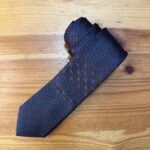 Corbata de seda azul con patrón de puntos morados y detalles dorados, ideal para eventos formales.