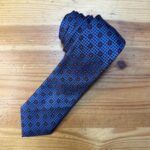 Corbata de seda azul con patrón geométrico y detalles en rojo, elegante y sofisticada para ocasiones especiales.