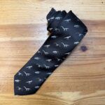 Corbata negra con diseño de dinosaurios en hilo plateado, elegante y moderna para ocasiones especiales.