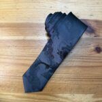 Corbata negra con patrón camuflaje para hombre, accesorio elegante para ocasiones formales.