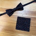 Corbata de pajarita negra con manchas naranjas, ideal para eventos elegantes y casuales.