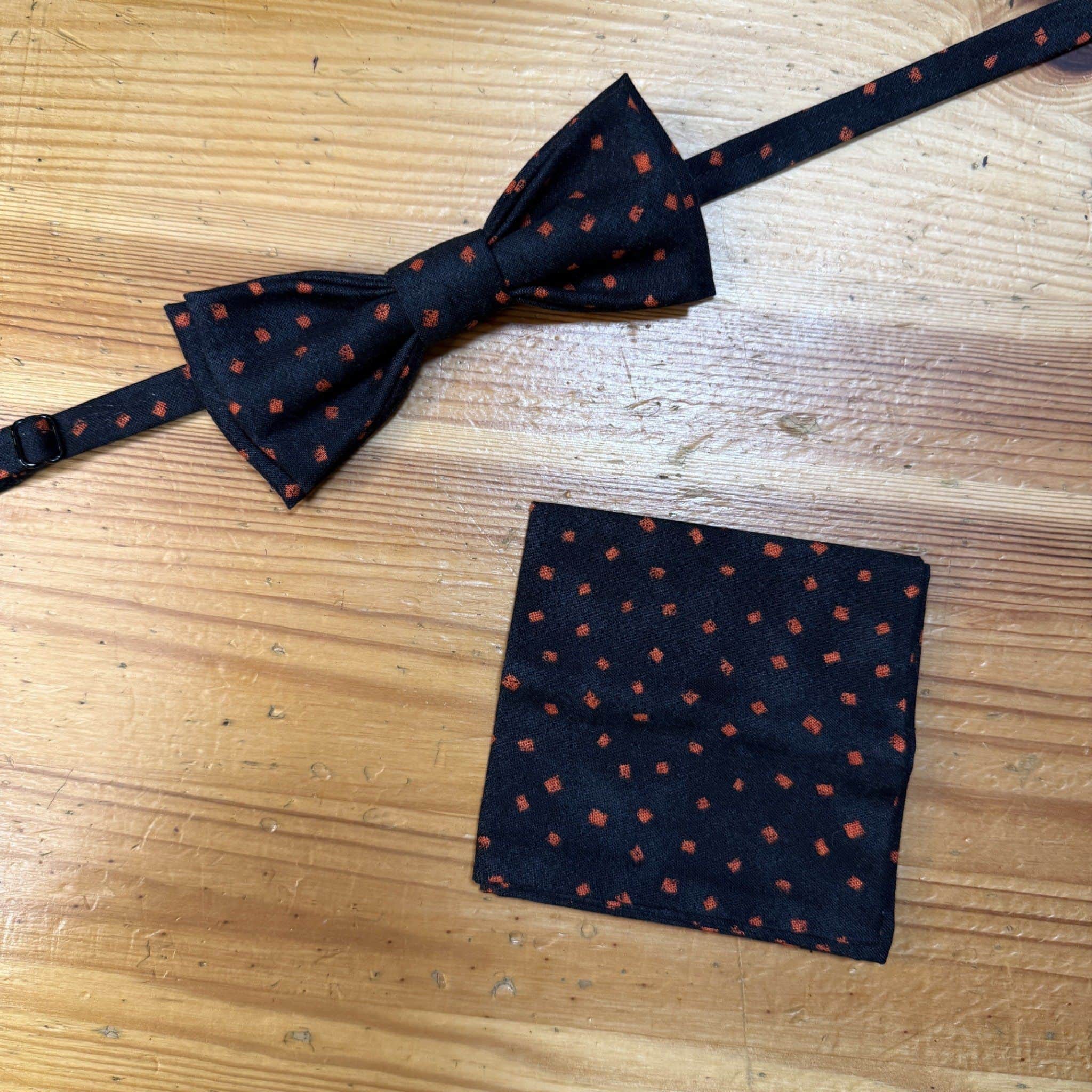 Corbata de pajarita negra con manchas naranjas, ideal para eventos elegantes y casuales.